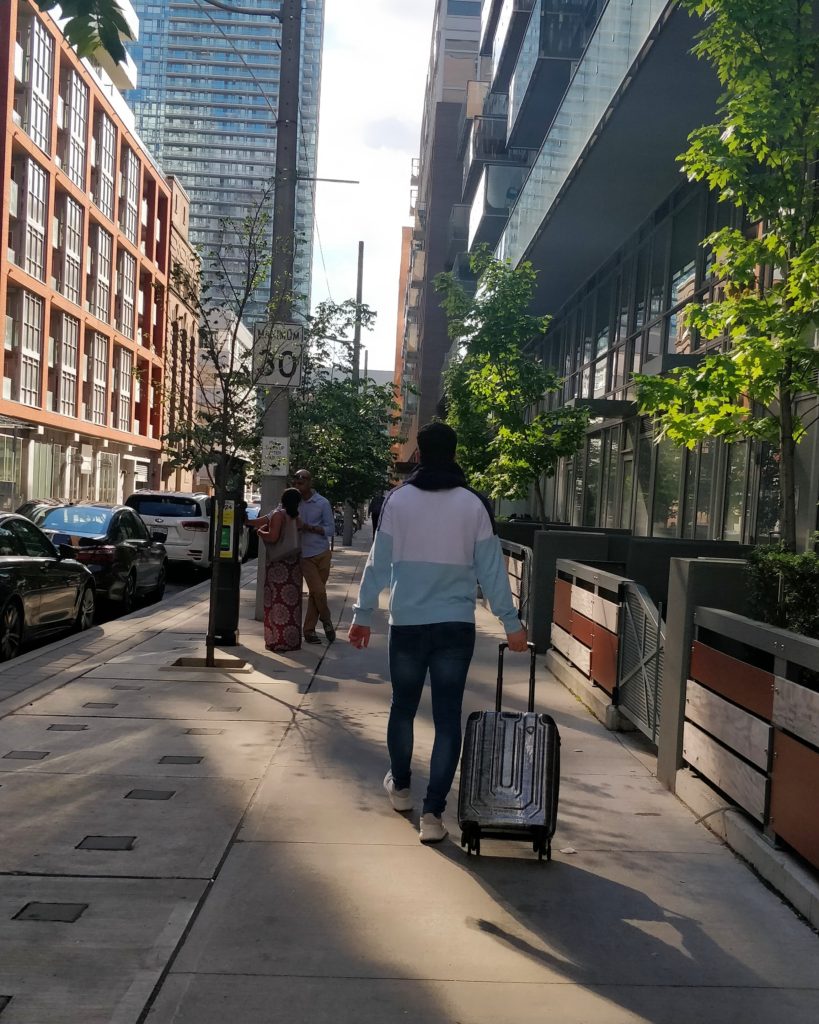 man walking down street with mia toro luggage
